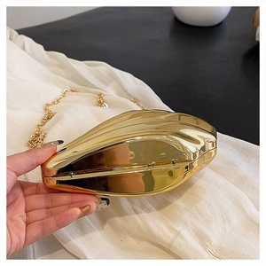 Macro detail of the golden shell-shaped evening bag with high-polish metallic finish