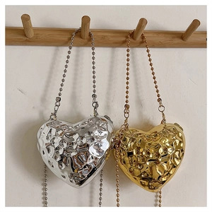 Detailed view of silver and gold heart bags with liquid metal hammered texture and bead chains