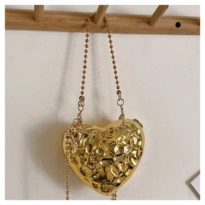 Detail of a heart-shaped gold metallic bag with a unique hammered lava texture and bead chain