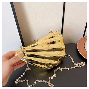 Detailed close-up of golden shell-shaped evening bag with metallic texture and chain