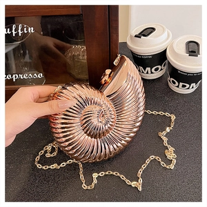 Macro shot of rose gold shell-shaped evening bag with spiral texture and gold chain