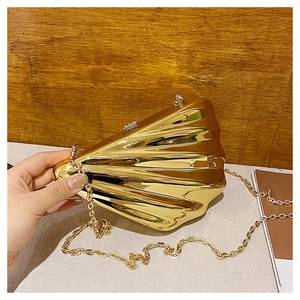 Detail of shell-shaped acrylic evening clutch with gold mirror finish and chain strap