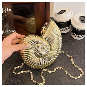 Detail of a golden conch-shaped evening clutch with textured spiral metal surface