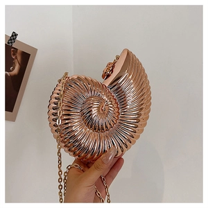 Macro shot of rose gold seashell evening clutch with textured metal finish and gold chain