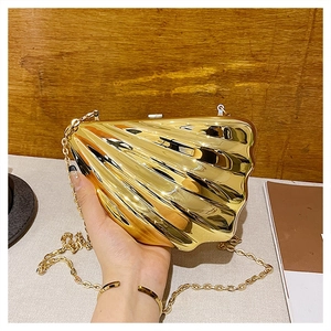 Detail of a gold shell evening bag with a metallic wave texture and slim chain strap
