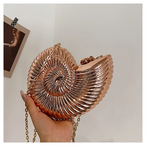 Macro view of shell-shaped acrylic evening bag with spiral metallic texture and chain