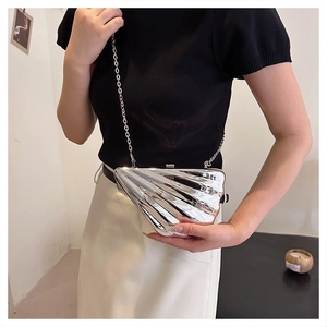 Detail of silver shell-shaped acrylic evening clutch bag with metallic mirror finish