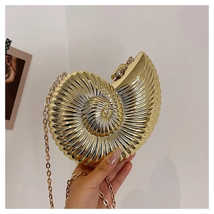 Detailed close-up of golden conch-shaped evening bag with metallic ribbed texture and chain