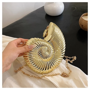 Detail of a luxury gold conch shell clutch bag with a metallic chain strap