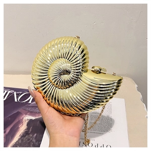 Detailed view of golden nautilus shell clutch bag with metallic texture and chain