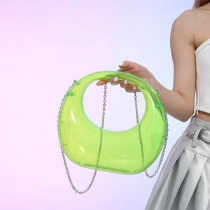 Neon green crescent acrylic evening bag with silver chain worn by a model