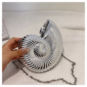 Detailed macro view of silver nautilus shell evening bag with radial texture and chain
