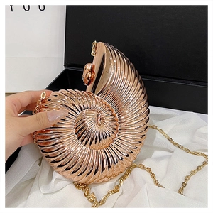Macro detail of rose gold nautilus shell evening bag with metal chain on silk