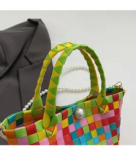 Détail d'un sac à main tissé en satin aux couleurs de l'arc-en-ciel avec perle décorative