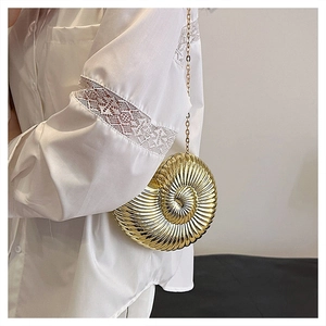 Close-up of golden nautilus shell evening bag with metallic chain and spiral textures