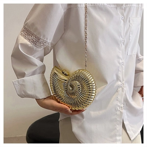 Detail of golden nautilus shell clutch bag with metallic wave texture and fine chain strap