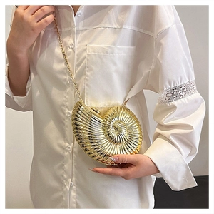 Detailed view of the golden nautilus shell clutch bag with metallic texture and chain