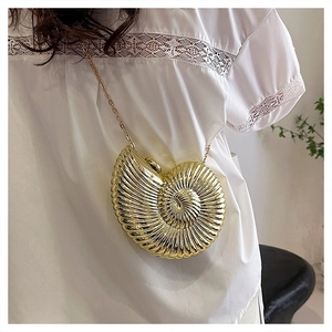 Detailed view of a gold nautilus shell clutch bag with a sleek metallic chain strap