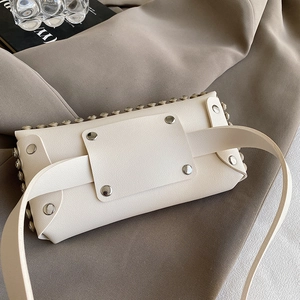 Sac à bandoulière chic en cuir blanc cassé avec rivets argentés sur présentoir stylé