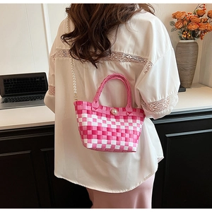 Détail du sac tissé à damier rose et blanc avec bandoulière en perles et bouton central
