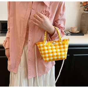 Détail d'un sac panier tressé jaune avec boucle en perles et longue bandoulière perle