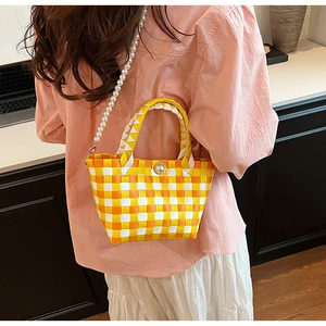 Gros plan du sac tissé avec bandoulière en perles et fermoir perle à motif écossais jaune