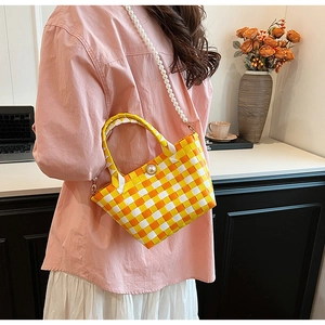 Détail du sac panier tressé à carreaux orange et jaune avec une grande boucle perle