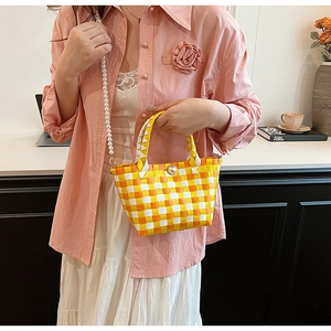 Détail du sac tressé à carreaux jaune et blanc avec fermoir perle et bandoulière