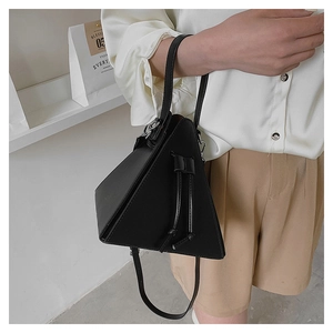 Detail of a black triangle leather handbag with drawstring accents and thin shoulder strap