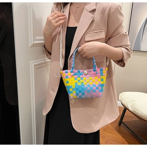 Détail d'un sac à main tissé coloré avec poignée en perles porté par le mannequin