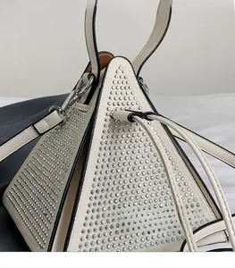 Détail du sac à main triangle blanc orné de strass argentés et de bords noirs contrastés