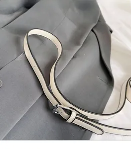 Bandoulière réglable en cuir crème avec boucle argentée et détails de bords noirs