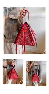 Détail d'un sac triangulaire rouge à rivets, avec poignée et bandoulière de haute qualité