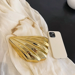 Glossy gold shell-shaped acrylic clutch bag with metallic mirror finish and gold chain strap