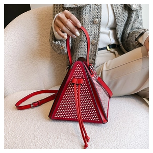 Vue détaillée d'un sac triangle rouge avec rivets argentés et fermeture à cordon