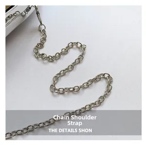 Close-up of a silver metal chain strap attached to a glossy acrylic evening clutch bag