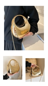 Detailed view of the gold bean-shaped mirrored handbag with its elegant metal chain strap
