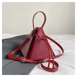 Détail du sac triangulaire rouge avec clous argentés et bandoulière réglable chic