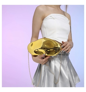 Close-up of golden irregular geometric cloud evening bag with reflective mirror finish