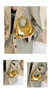Close-up of golden crescent hobo bag featuring mirror finish and metal chain strap