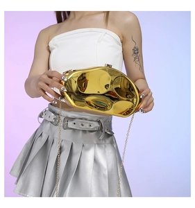 Detail of gold pebble clutch bag with polished mirror finish and thin metal chain strap