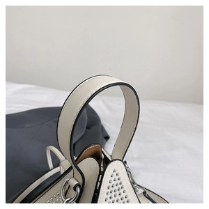 Détail du sac en cuir crème avec clous argentés et coutures de ferrures métalliques