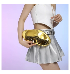 Close-up of golden irregular stone-shaped clutch bag with sleek metal chain and mirror finish