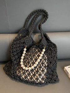 Detail of black hollow mesh woven bag with white pearl strap and canvas drawstring liner