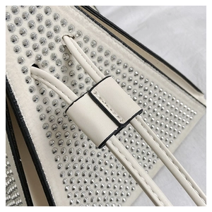 Détails de strass argentés sur un sac triangle en cuir blanc avec cordon de serrage