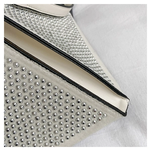 Détail d'un sac triangle blanc avec clous argentés et bords laqués noirs