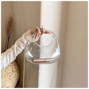 Detail of transparent acrylic half-moon bag with gold chain and top circular handle