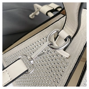 Détail du sac triangulaire blanc orné de strass brillants et de ferrures argentées
