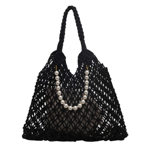 Detail of black hollow mesh woven bag with large white pearls and a drawstring inner pouch
