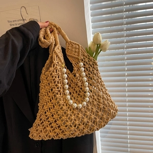 Detail of hand-woven mesh beach bag featuring elegant faux pearl handle and khaki macrame